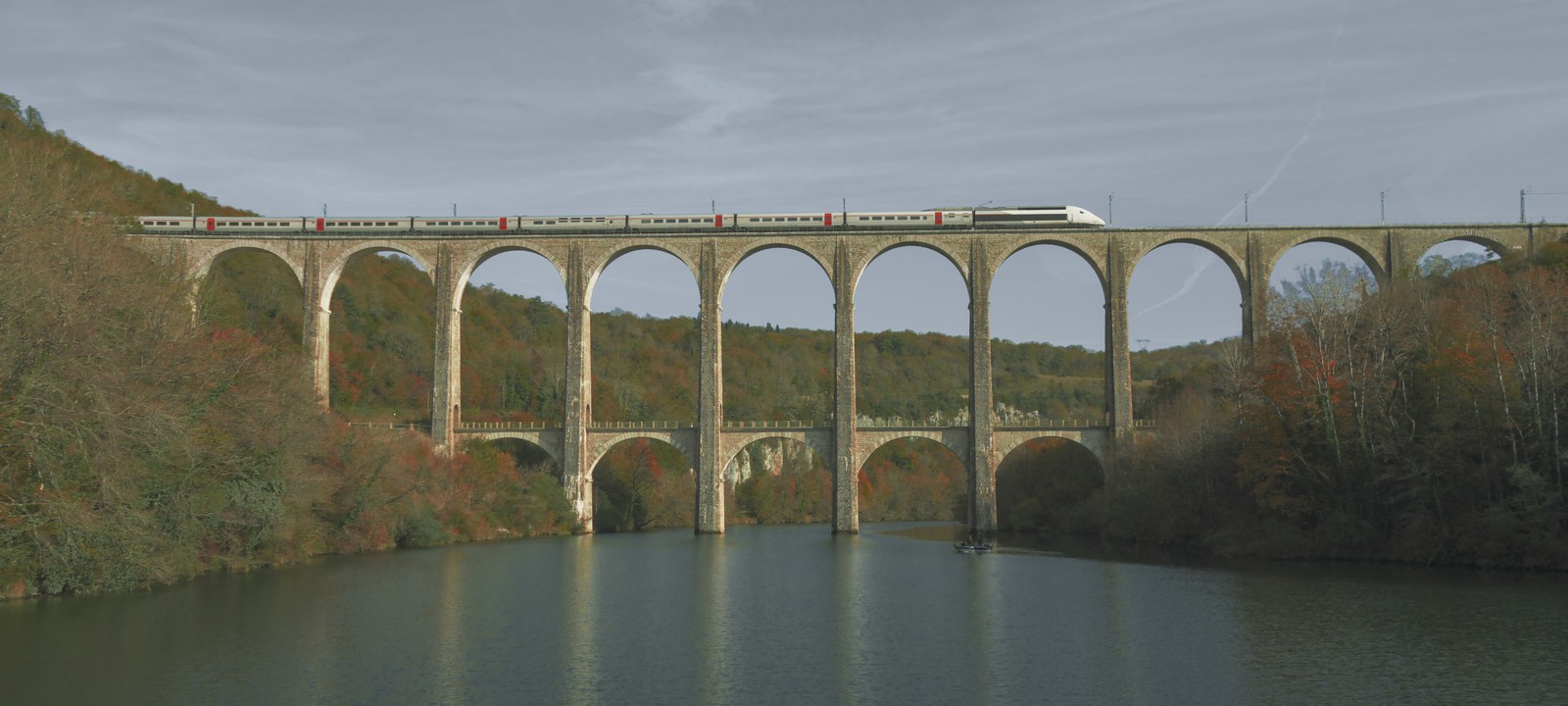 Train traversant un viaduc de pierre au-dessus d’une vallée boisée
