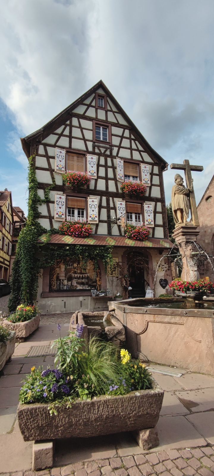 Maison à colombages et fontaine fleurie dans un village alsacien