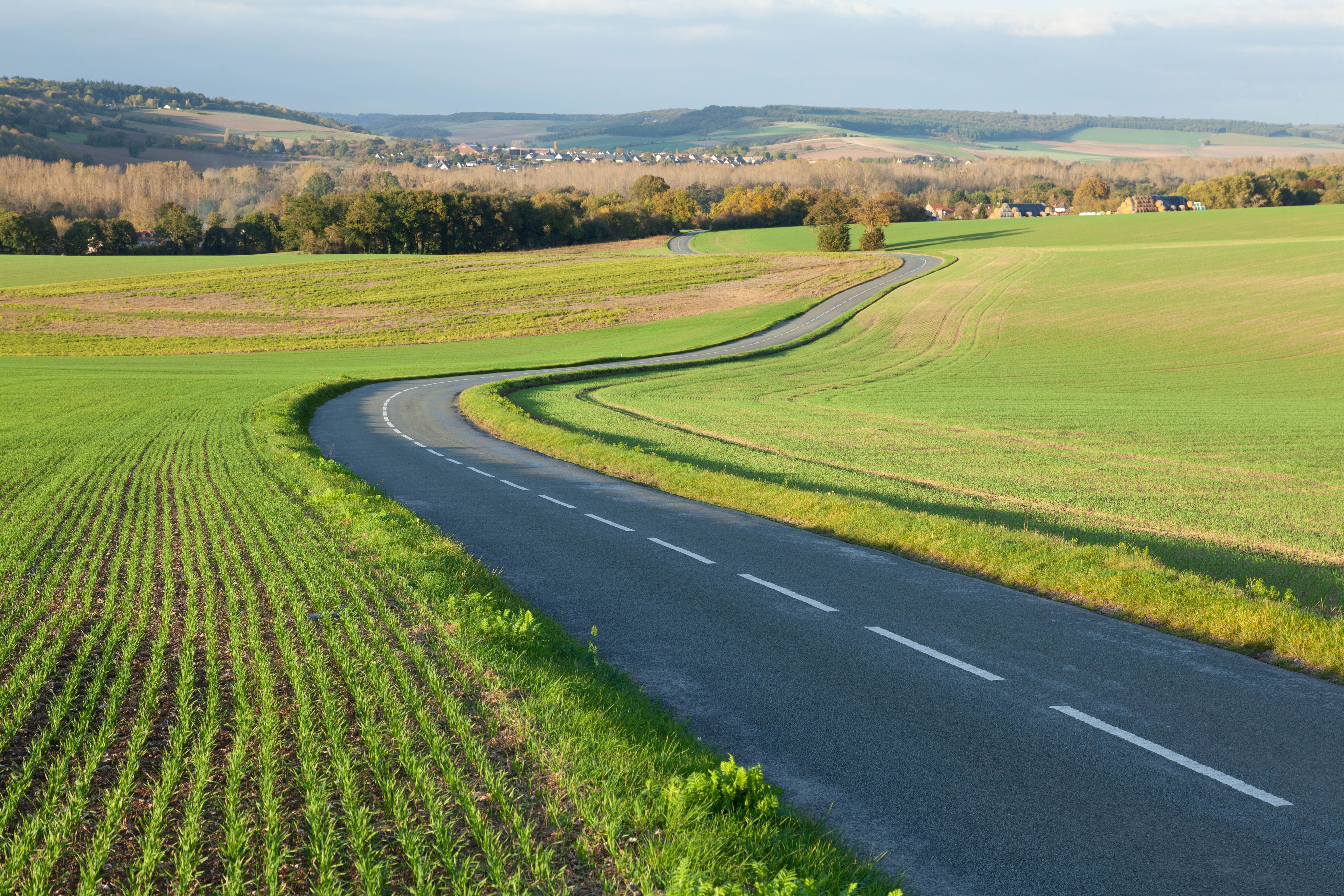 Route sinueuse traversant des champs ouverts dans la campagne française
