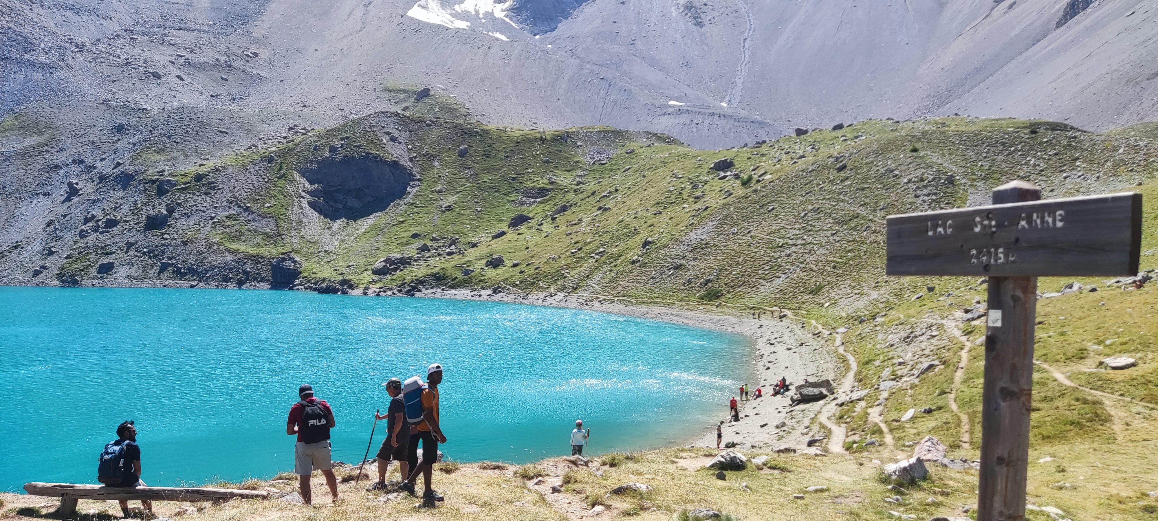 Randonneurs arrivant au bord d’un lac alpin turquoise