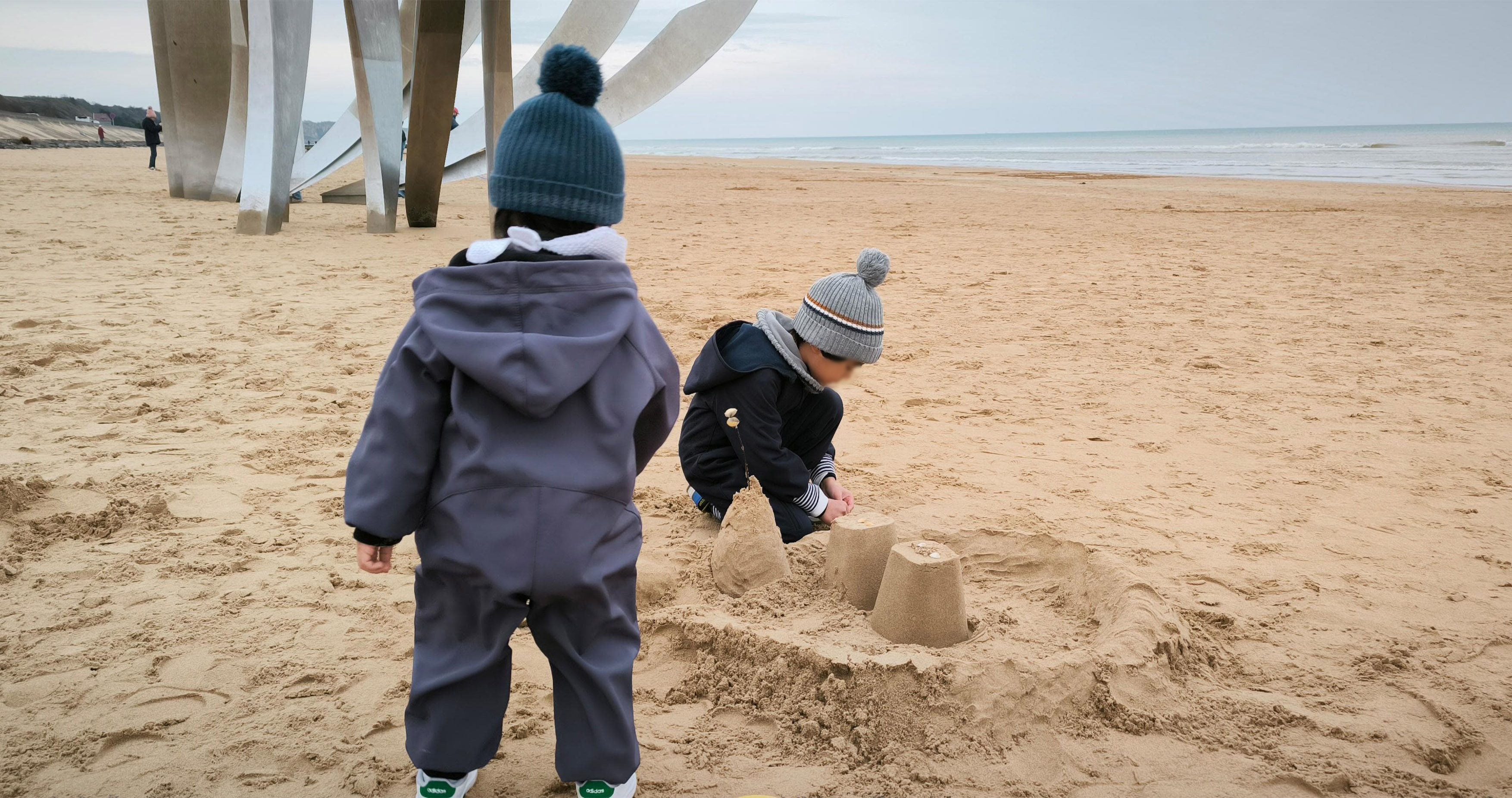 Deux enfants construisant un château de sable sur une plage calme